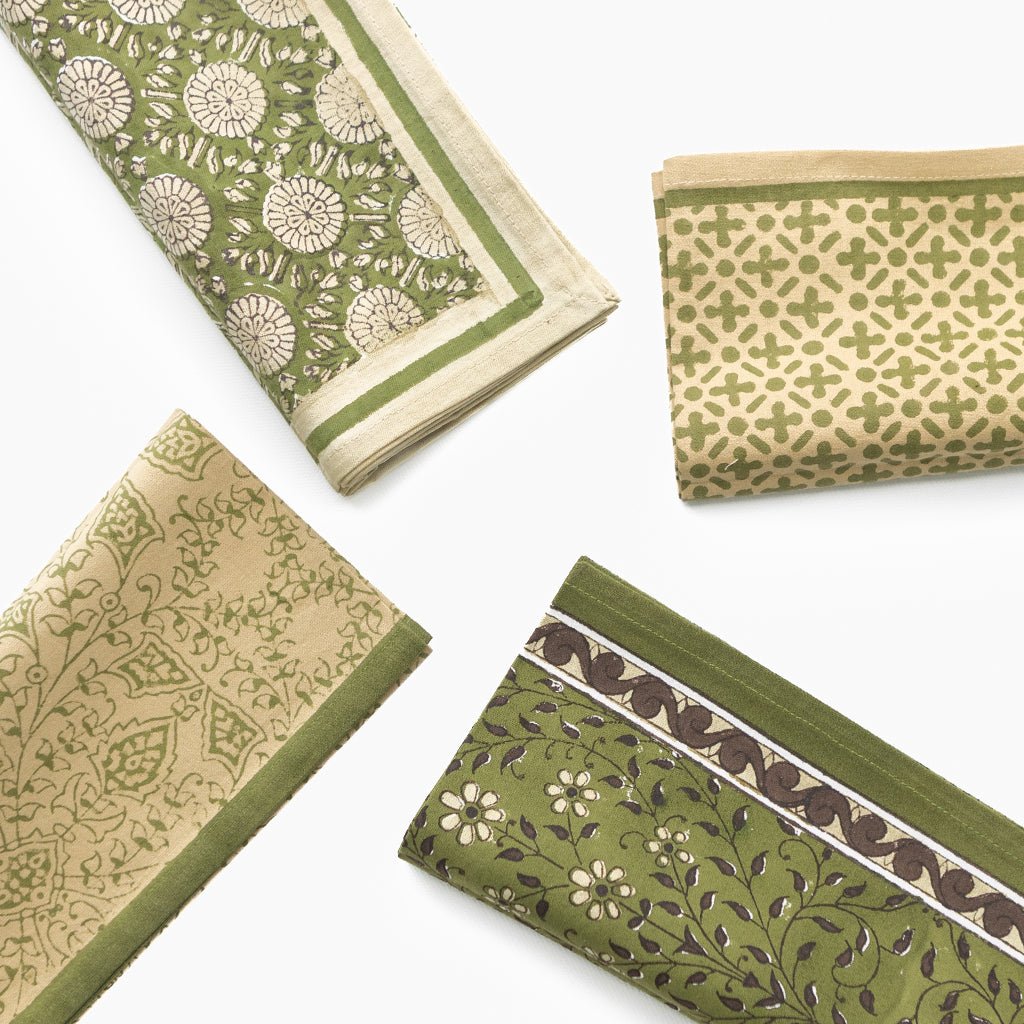 Set of green and beige patterned fabric napkins on a white background