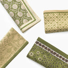 Set of green and beige patterned fabric napkins on a white background