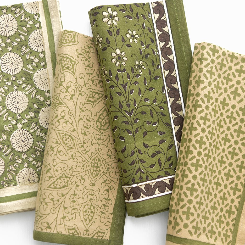 Collection of green and beige patterned napkins on a white background