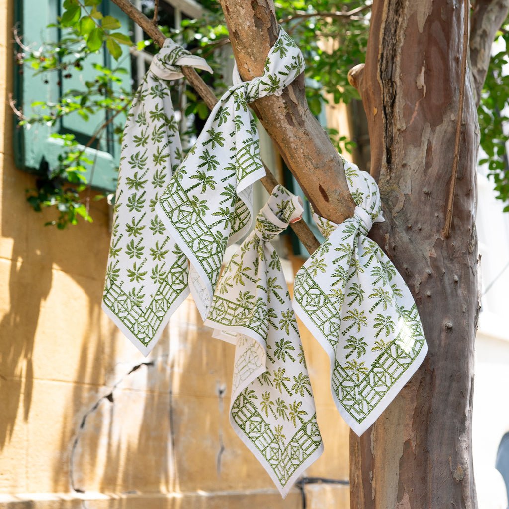 Green and white patterned napkins hanging on a tree branch.
