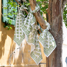 Green and white patterned napkins hanging on a tree branch.