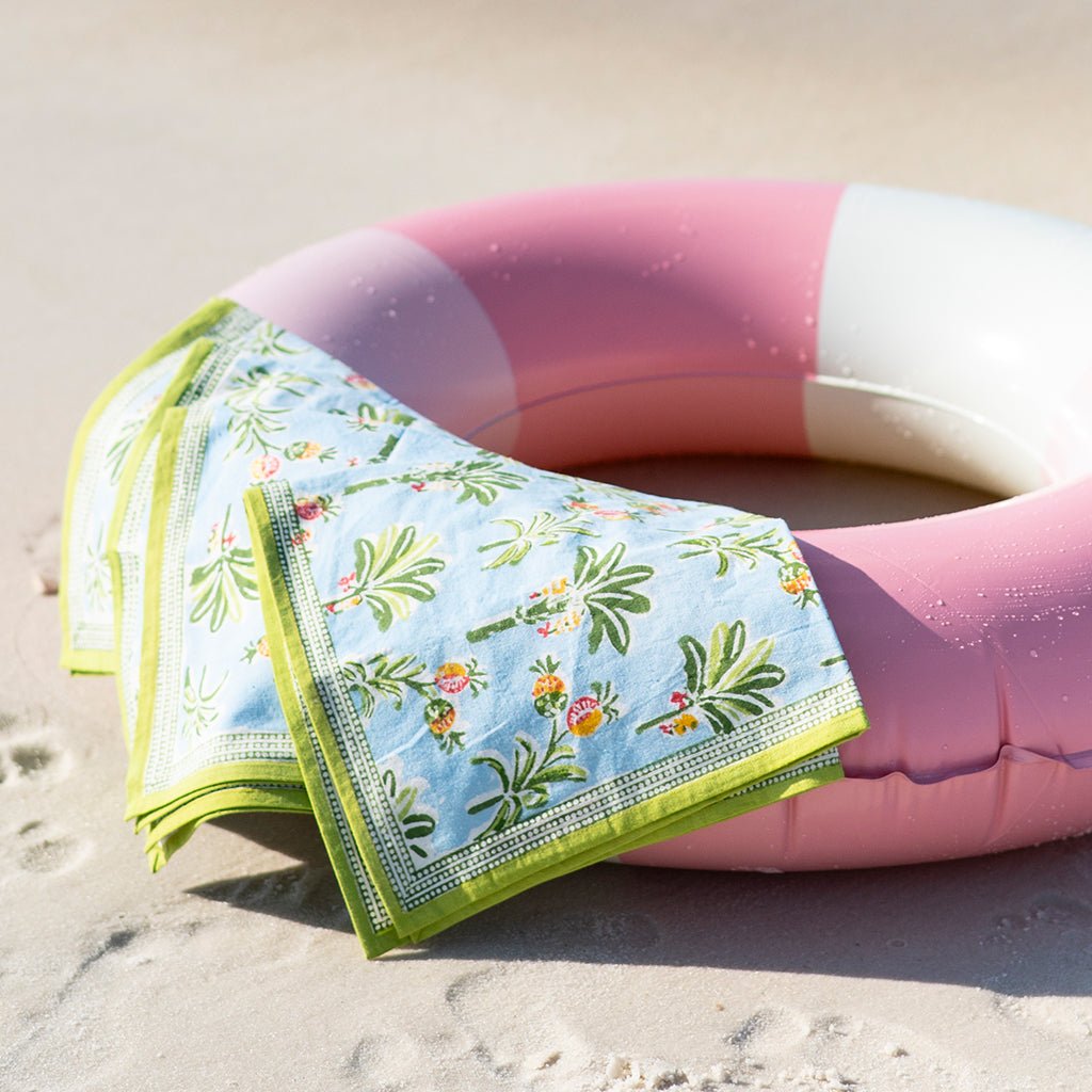 Tropical patterned towel on a pink and white inflatable ring on sand