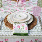 Table setting with floral tablecloth, plates, and napkin on a decorative table.