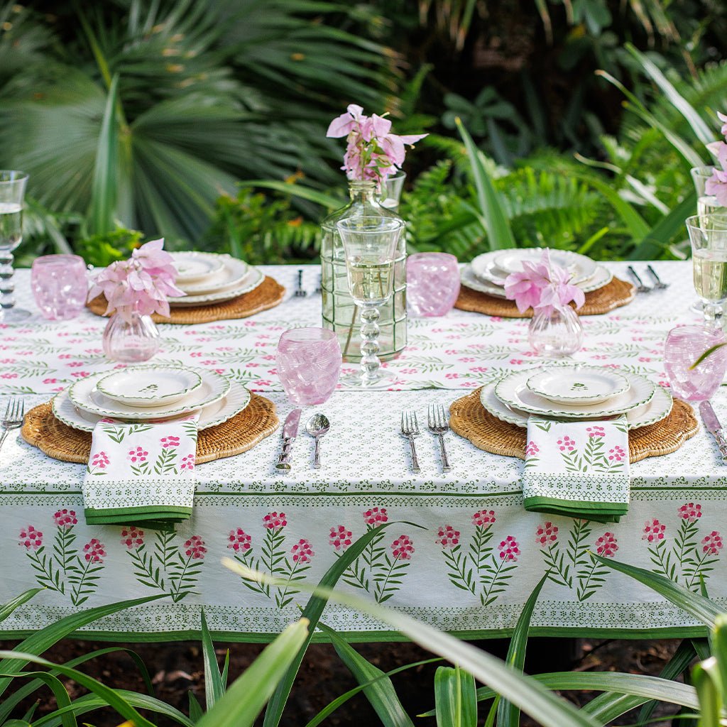 Table setting with floral tablecloth and pink flowers in a garden setting