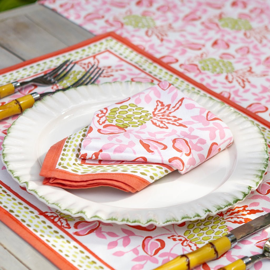 Colorful table setting with floral napkins and cutlery on a patterned tablecloth.