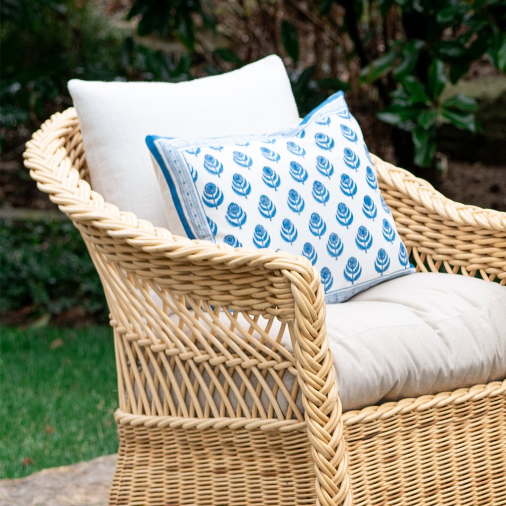 Wicker chair with white and patterned blue cushions outdoors