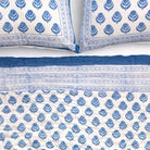 Blue and white patterned quilt and pillows on a white background