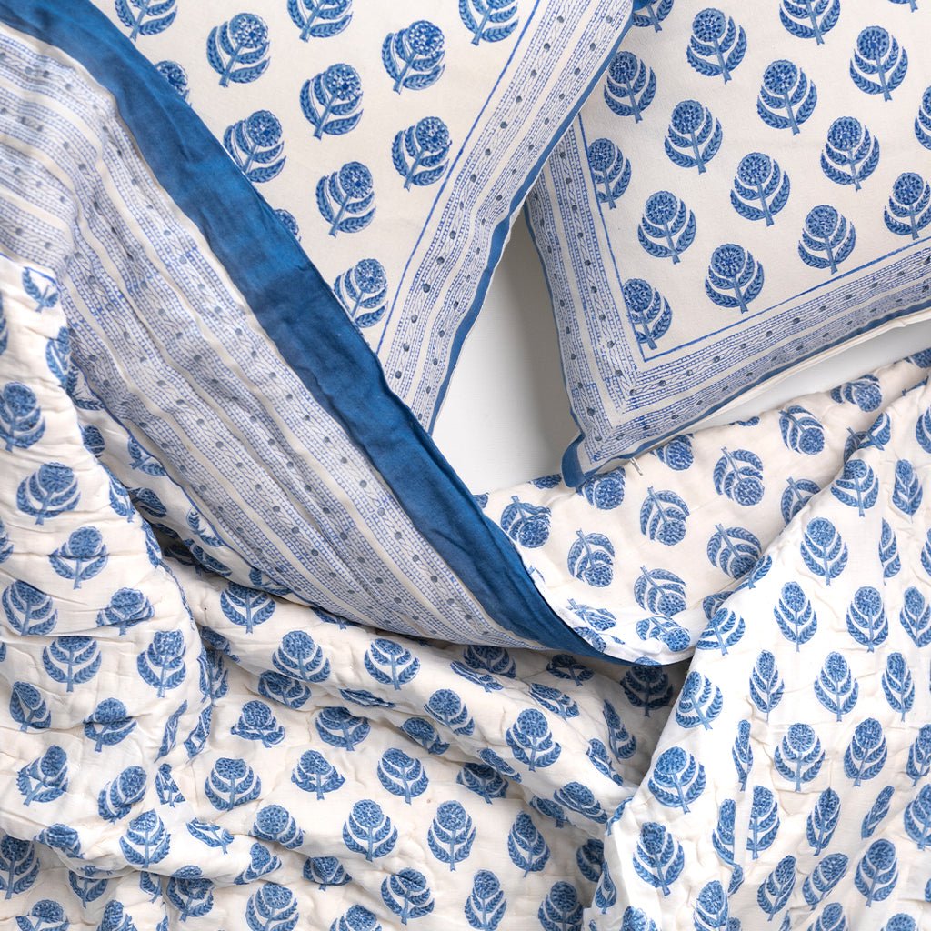 Blue floral patterned quilt and pillows on a white background