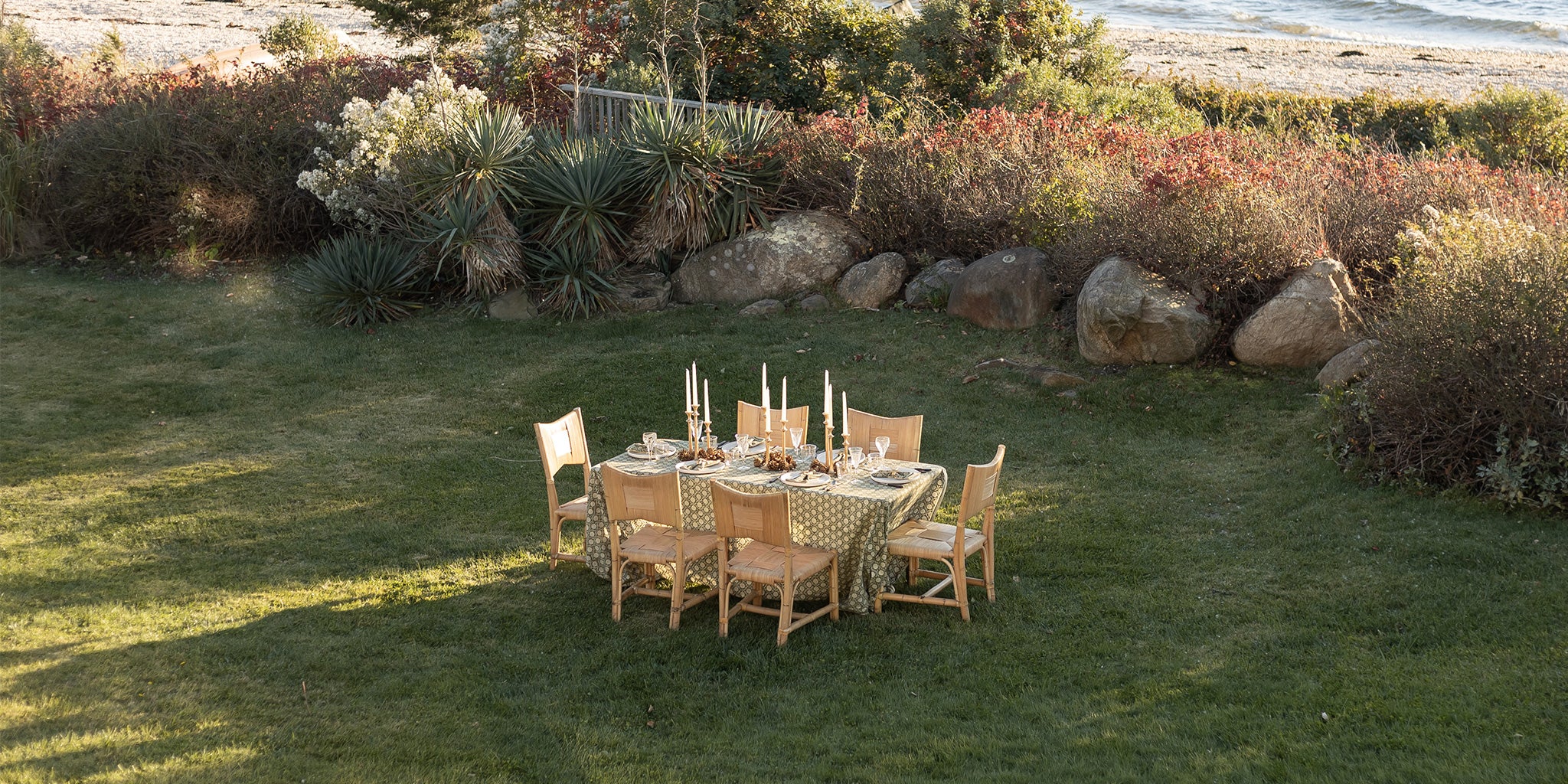 Outdoor dining setup on a grassy area with a scenic background