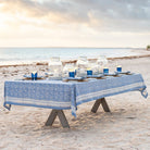 Table set with blue tablecloth and beach decor on a sandy beach.