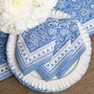 Blue and white patterned napkins on a white plate with a wooden surface background.