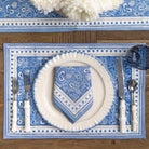 Table setting with blue and white patterned placemat, plate, napkin, and cutlery.