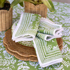 Green and white patterned napkins on a table with woven placemats.