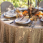 Decorated outdoor table setting with fall-themed elements on a patterned tablecloth.