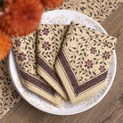 Three napkins with floral patterns on a white plate on a wooden surface.