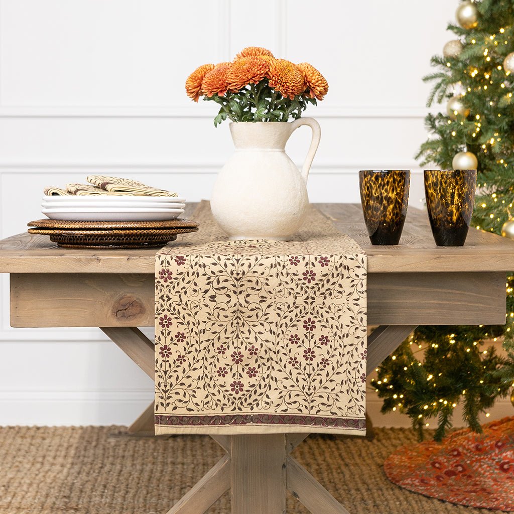Decorative table setting with a pitcher, glasses, and floral arrangement in a home setting.