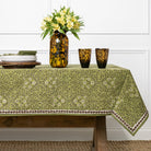 Table setting with a green floral tablecloth, vase with flowers, and leopard print cups.