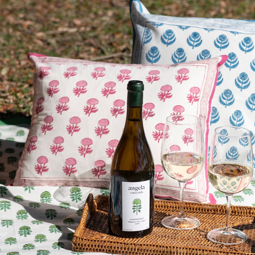 Wine bottle and glasses on a tray with decorative pillows in the background
