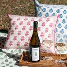 Wine bottle and glasses on a tray with decorative pillows in the background