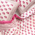 Pink and white floral patterned quilt and pillows.