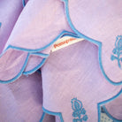 Close-up of a purple fabric with blue embroidery and a 'Pomegranate' label.