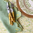 Set of cutlery with bamboo handles on a green napkin with a floral pattern.