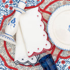 Decorative table setting with white plates, blue and red patterned placemats, candlestick, and a blue glass.