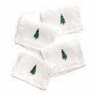 Set of white napkins with embroidered Christmas tree designs on a white background