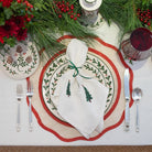 Christmas-themed table setting with decorative plates, napkin, and cutlery.