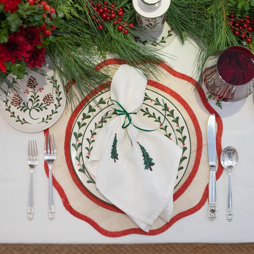 Christmas-themed table setting with decorative plates, napkin, and cutlery.