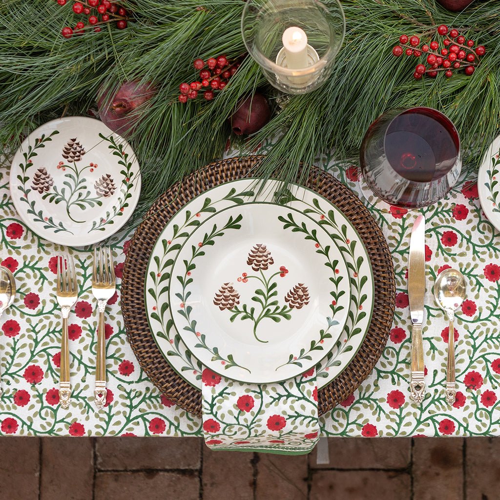 Christmas-themed table setting with floral-patterned plates, red berries, and greenery.