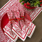 Red and white patterned napkins on a red plate with a decorative plant on a wooden table.