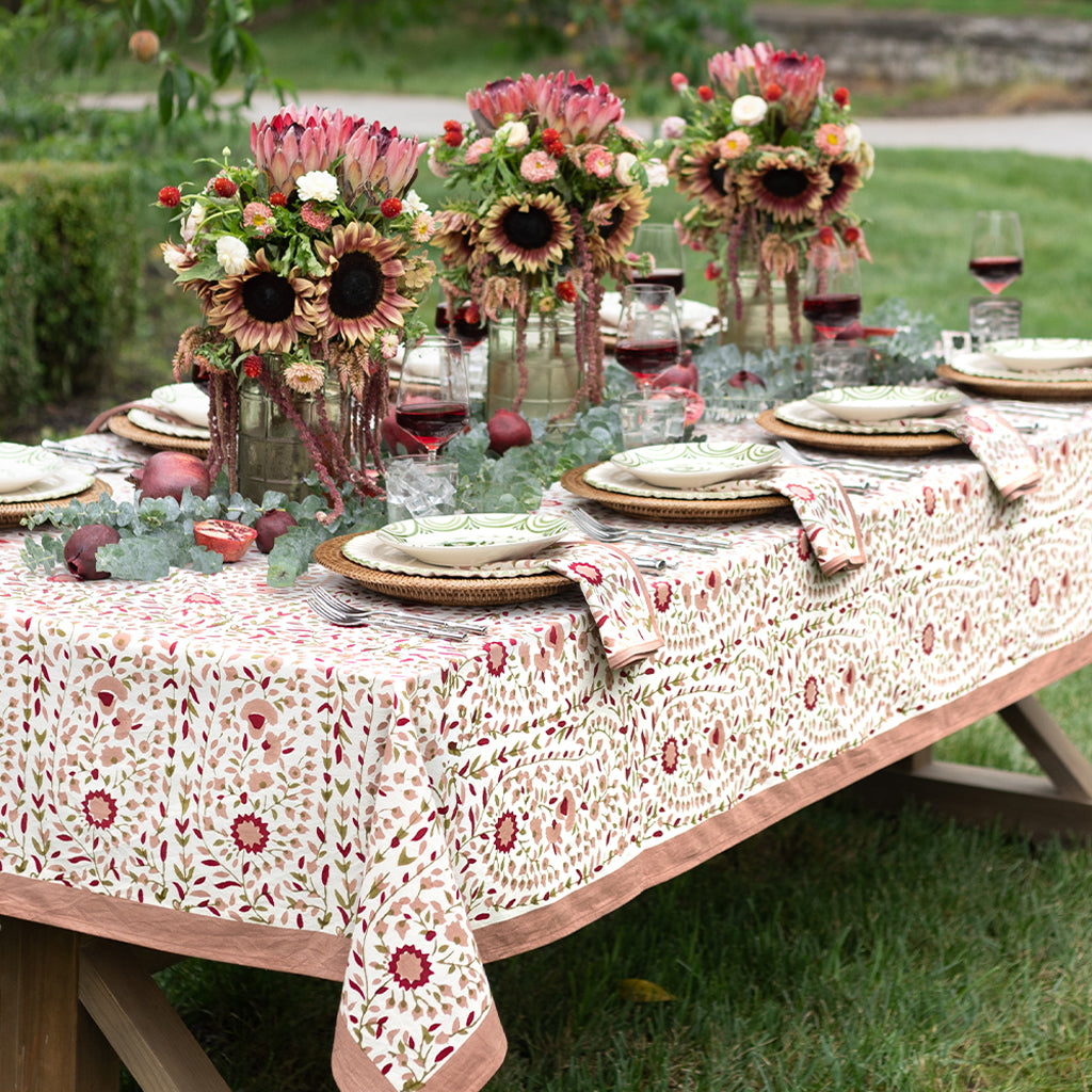 Decorated outdoor table with floral centerpieces and patterned tablecloth.