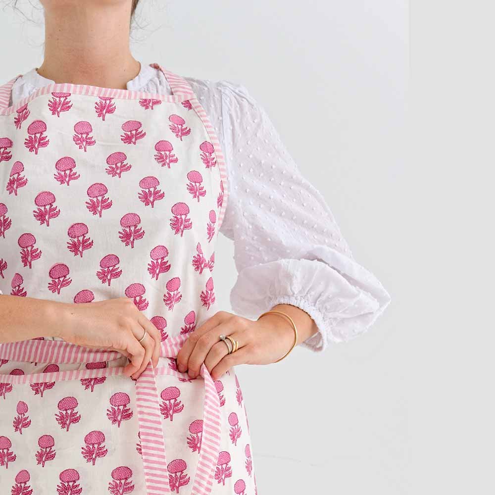 Pink and white floral print apron with stripe tie details. 