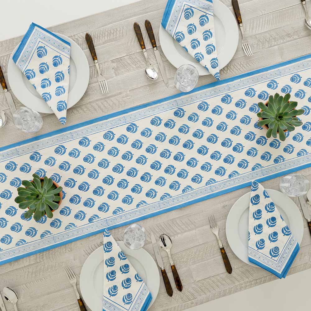 Overhead shot of table runner and matching napkins folded on white plates. 