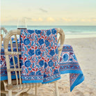 Tea towel with hues of blue and paprika orange hanging on the back of a chair at a beach dinner party. 