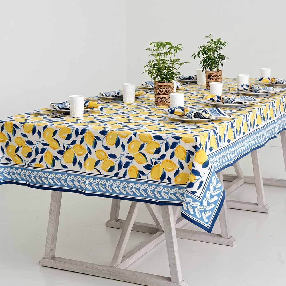 Dinner table with plants and white glasses with tablecloth and matching napkins. 