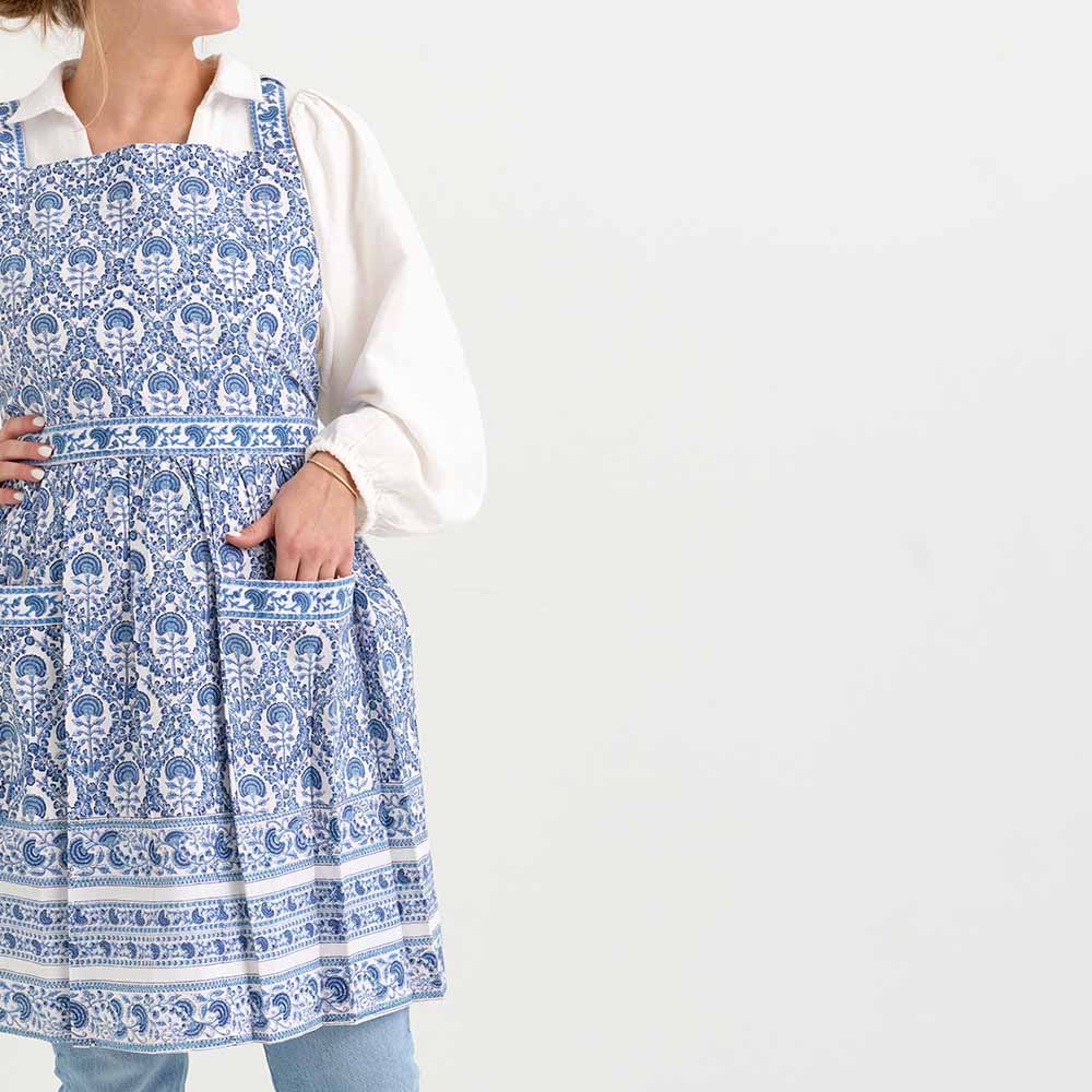 Blue and white floral pattern on a pleated apron with ties behind the neck and behind the back. 