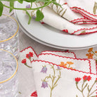 Floral napkin set with red scalloped stitch. 