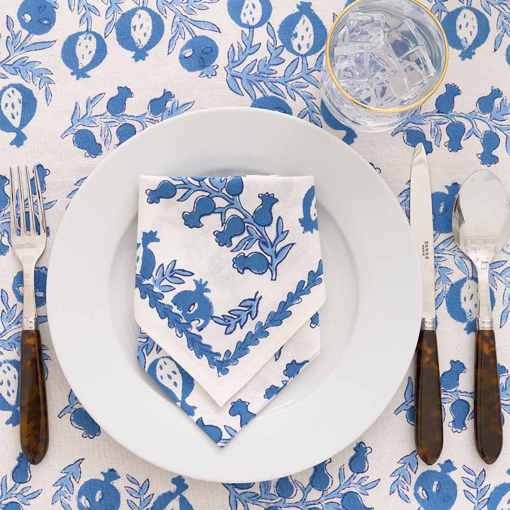 Tablecloth with matching napkin folded on white plate. 