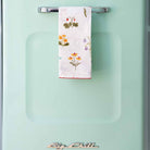 Tea towel hanging on a turquoise blue refrigerator. 