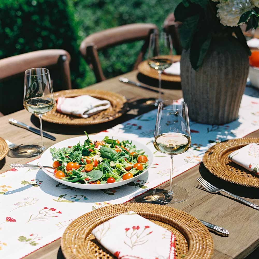 Linen table runner paired with linen napkins on outdoor dinner table. 