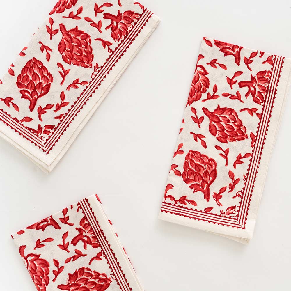 Red and white Dancing Artichoke napkin with lined border. 