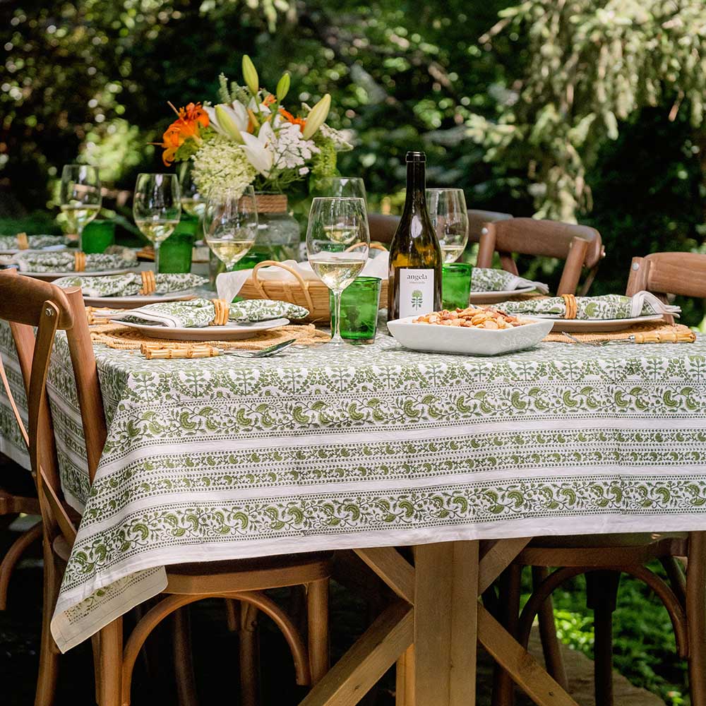 Caroline Green Tablecloth on an outdoor dinner table with wine, flowers, and food. 