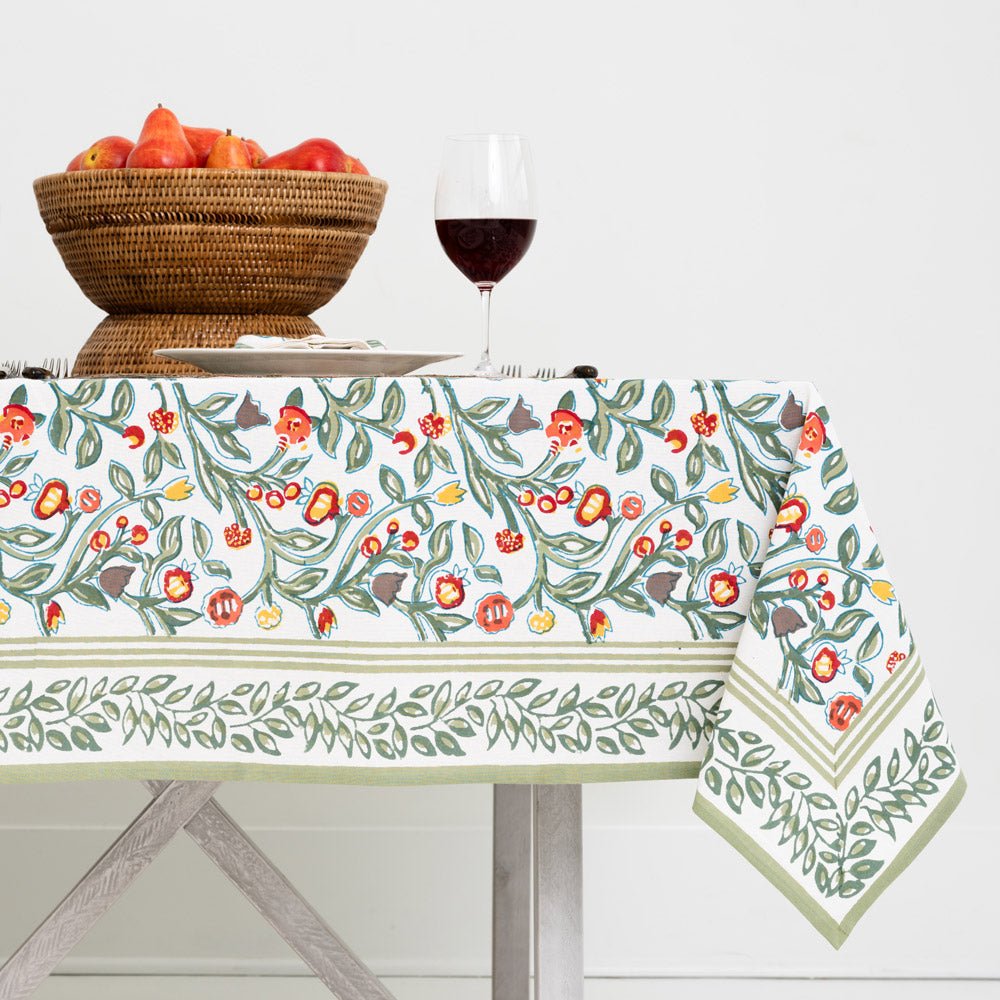 tablecloth with floral pattern in shades of sage green, crimson, marigold and deep orange on a white background