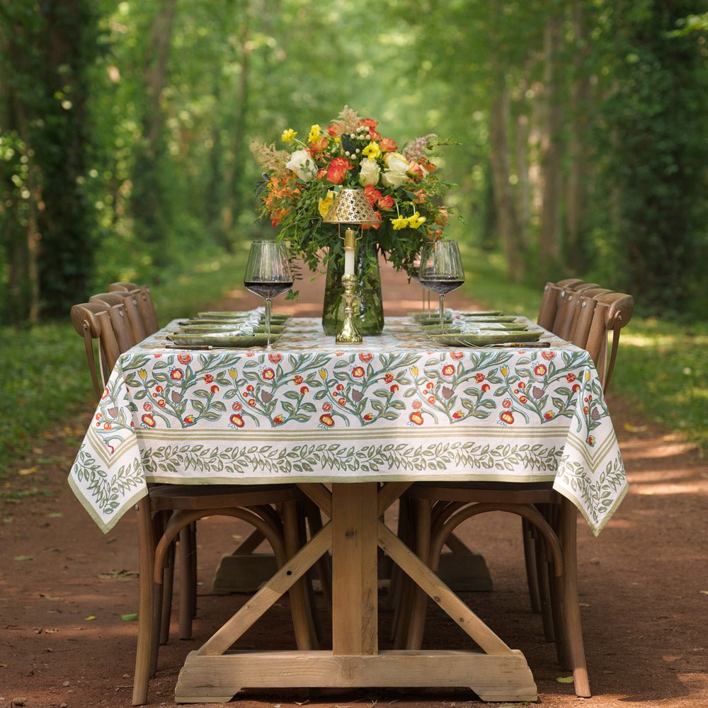 tablecloth with floral pattern in shades of sage green, crimson, marigold and deep orange on a table outdoors