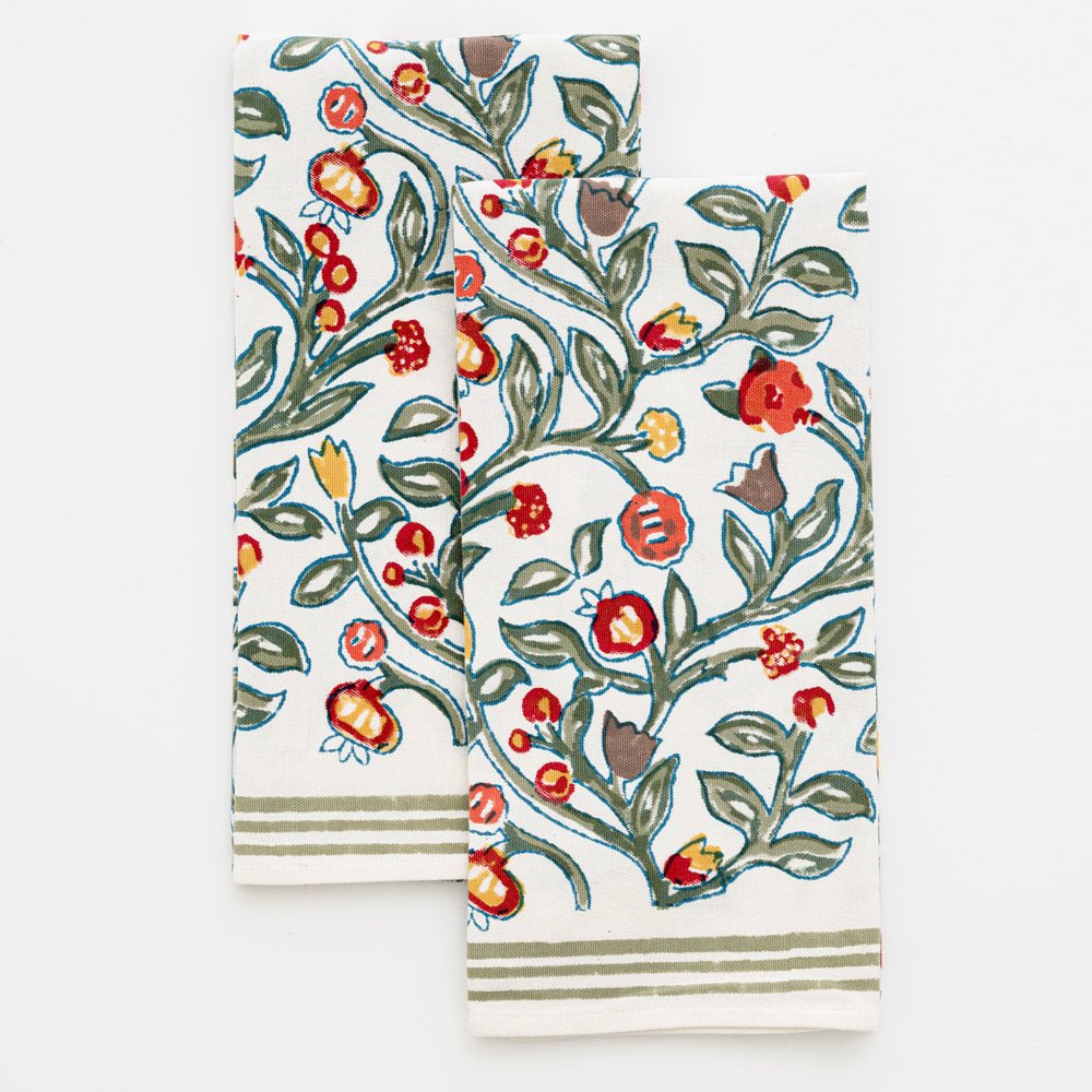 two tea towels with floral pattern in shades of sage green, crimson, marigold and deep orange on a white background