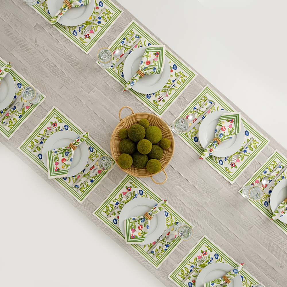 Long dinner table with placemats and matching napkins with a basket centerpiece. 