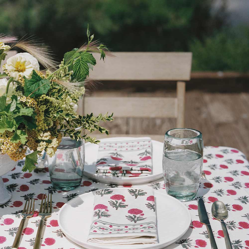 Outdoor table with napkins, tablecloth, and flower bouquet. 