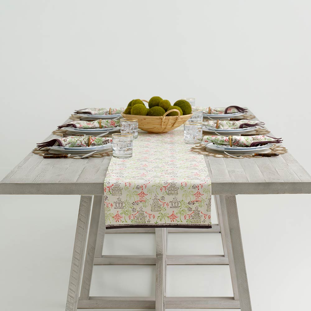 Table runner on wooden table with matching napkins on dinner plates. 